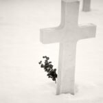 Black and white photograph by Bernard Donjean that shows the cross of an American soldier decorated with a plant branch (name of the photograph : American Cemetery, #1)