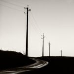 Black and white photograph by Bernard Donjean that shows four electric poles photographied against the light (name of the photograph : Standing in Line)