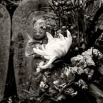 Black and white photograph by Bernard Donjean that shows a bunch of flowers placed in front of a Jizo stone statue (name of the photograph : Flowered Jizo Stone)