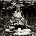 Black and white photograph by Bernard Donjean that shows the Central Buddha at Adashino Nenbutsu-ji temple (name of the photograph : Offerings to Buddha)