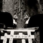 Black and white photograph by Bernard Donjean that shows a pair of scaled models torii in front of a pair of stone fox statues (name of the photograph : Torii and Foxes)