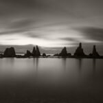 Black and white photograph by Bernard Donjean that shows a group of rock formations called Hashigui-Iwa (name of the photograph : Dawn over Hashigui-Iwa)