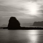 Black and white photograph by Bernard Donjean that shows the shadow of a rockformation during the sunset in Tainoura bay (name of the photograph : Sunset on Tainoura Bay)