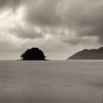 Black and white photograph by Bernard Donjean that shows a small island (called Ao island) covered by threatening sky (name of the photograph : Ao Island, #2)