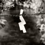 Black and white photograph by Bernard Donjean that shows a japanese shide suspended to a rope above a stream (name of the photograph : Stream Shide)