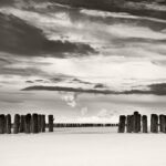Black and white photograph by Bernard Donjean that shows two rows of brakewater on a beach in Zeeland (name of the photograph : Opening to the Next Row)