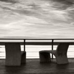 Black and white photograph by Bernard Donjean that shows two side by side concrete seafront chairs on the seawall of Ostende (name of the photograph : Concrete Seafront Chairs)