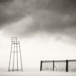 Black and white photograph by Bernard Donjean that shows a watch chair and the end of a sand fence on the beach of Knokke (name of the photograph : Watch Chair, #1)